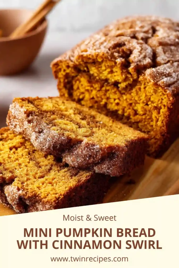 Mini pumpkin bread loaves with cinnamon sugar swirl arranged on a board.